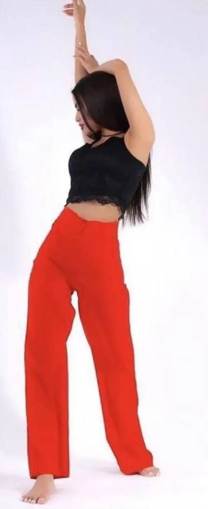 beautiful young brunette woman dancing in black lace crop top and bright red wide leg trousers, white seamless studio background, fashion editorial photography, natural soft lighting, full body pose