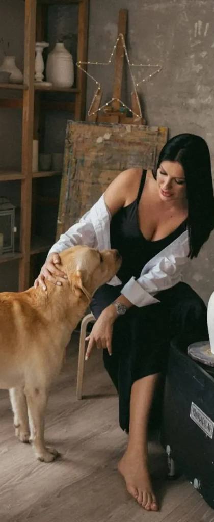 beautiful brunette woman petting golden retriever in modern loft apartment with elegant black dress
