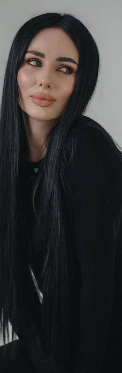 beautiful brunette woman with long straight black hair wearing elegant black dress in minimalist studio portrait
