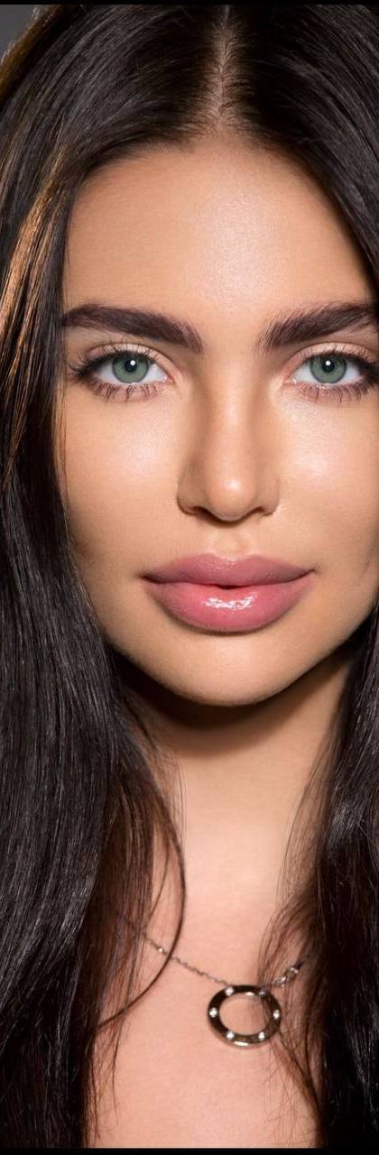 Ultra realistic beauty portrait of a stunning woman with long dark brown glossy hair, mesmerizing emerald green eyes, flawless porcelain skin, full natural lips, perfectly shaped eyebrows, soft studio lighting, luxury skincare campaign, high-end beauty editorial, extremely detailed, 8K.