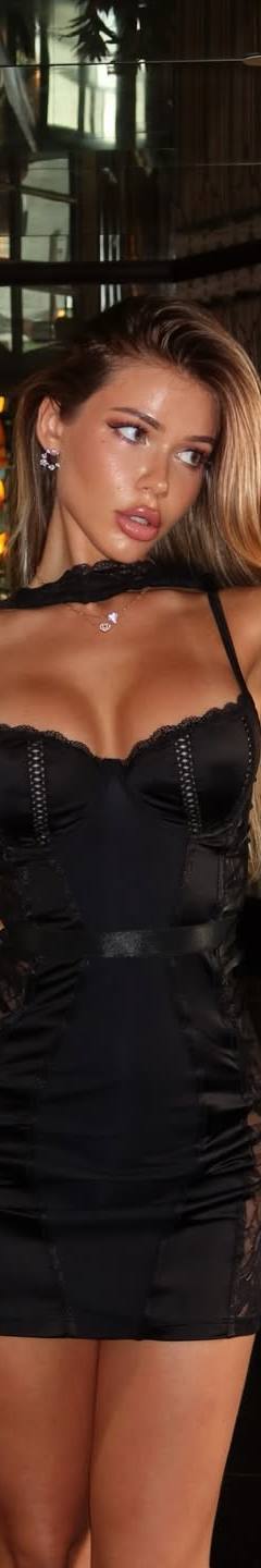Elegant blonde woman in a black mini dress posing in a luxurious hotel lobby