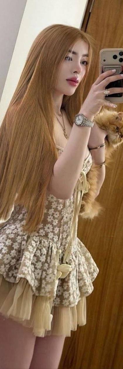 beautiful woman with long auburn hair taking mirror selfie while holding fluffy ginger cat