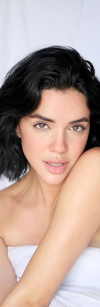 Beautiful brunette luxury escort model posing in bed with natural makeup and short black hair